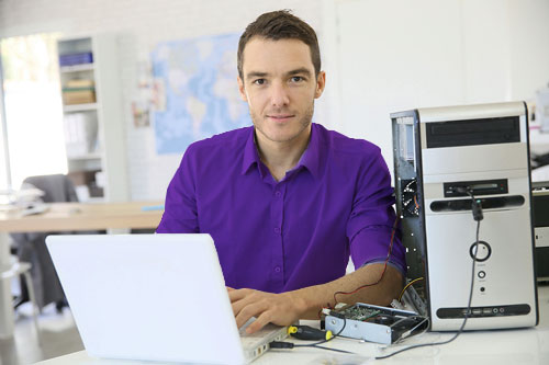 متخصص شبکه ارغوان در حال تعمیر تجهیزات شبکه با لپ تاپ و کیس کامپیوتر